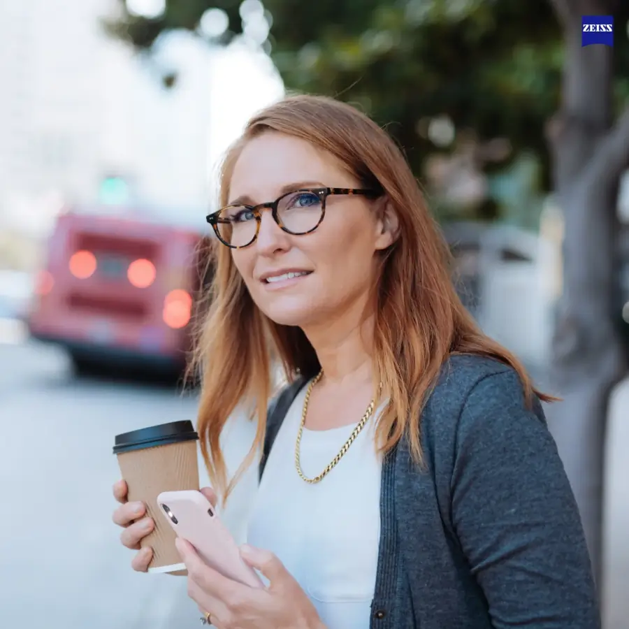 Woman in round tortoise frames with Zeiss SmartLife lenses on a city street