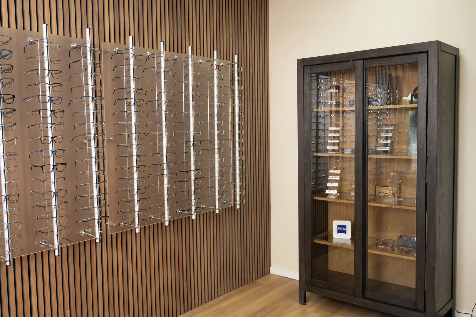 Wall-mounted eyeglass racks beside a glass-front display cabinet
