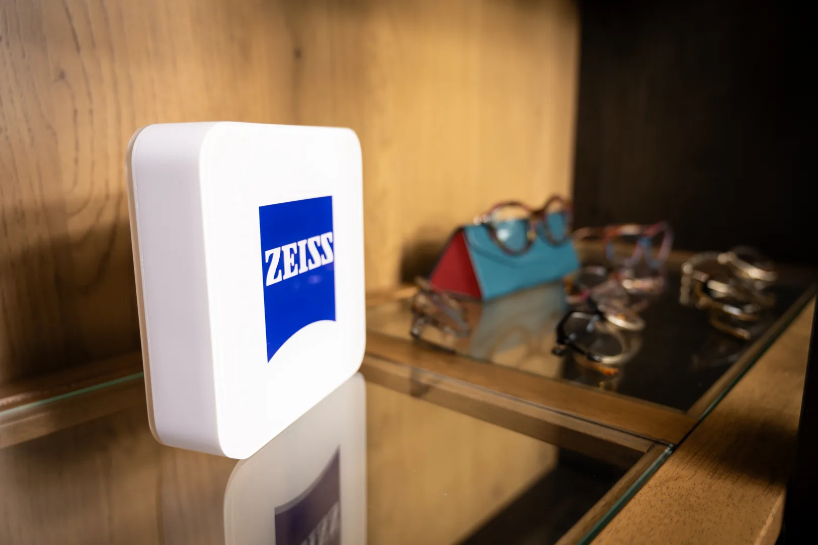 A lit Zeiss lenses sign on a display shelf of frames